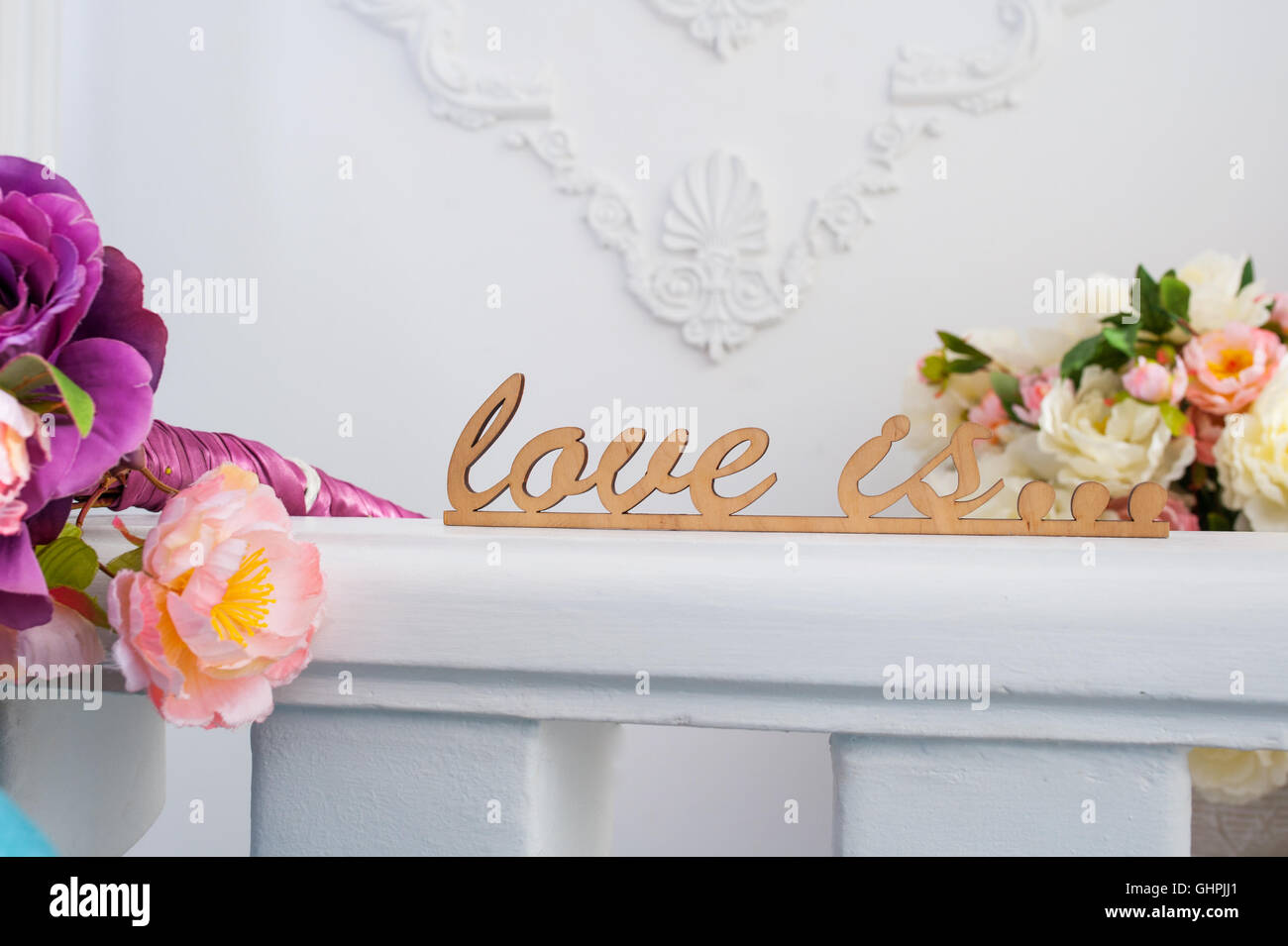 wooden words love is with flowers in studio Stock Photo