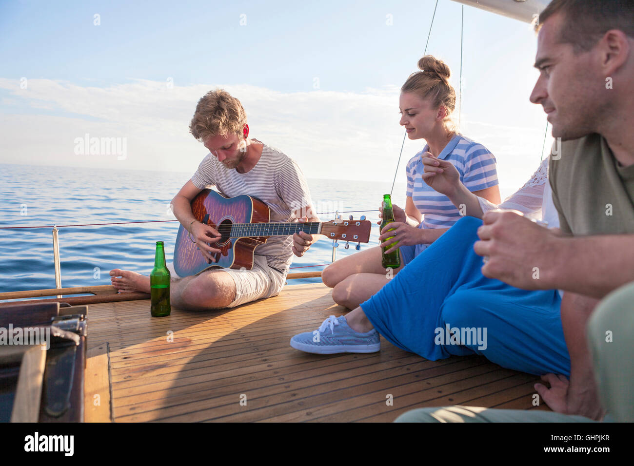 Young man playing guitar on sailboat Stock Photo