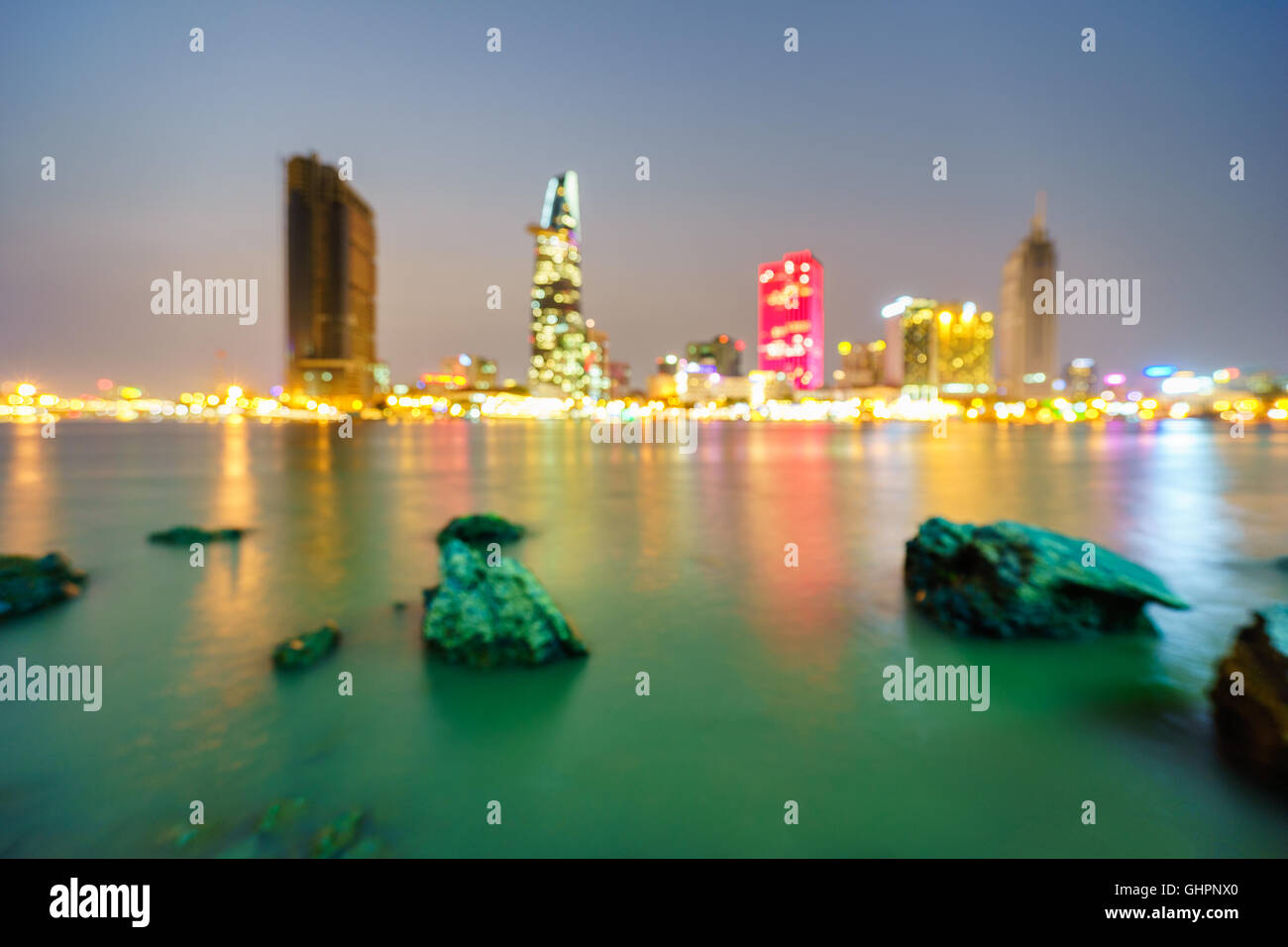 Ho Chi Minh city skyline and the Saigon river in twilight with defocused bokeh lights as abstract background, Vietnam. Stock Photo