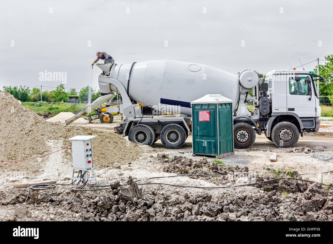 Driver is washing mixer truck with water jet, after concrete casting