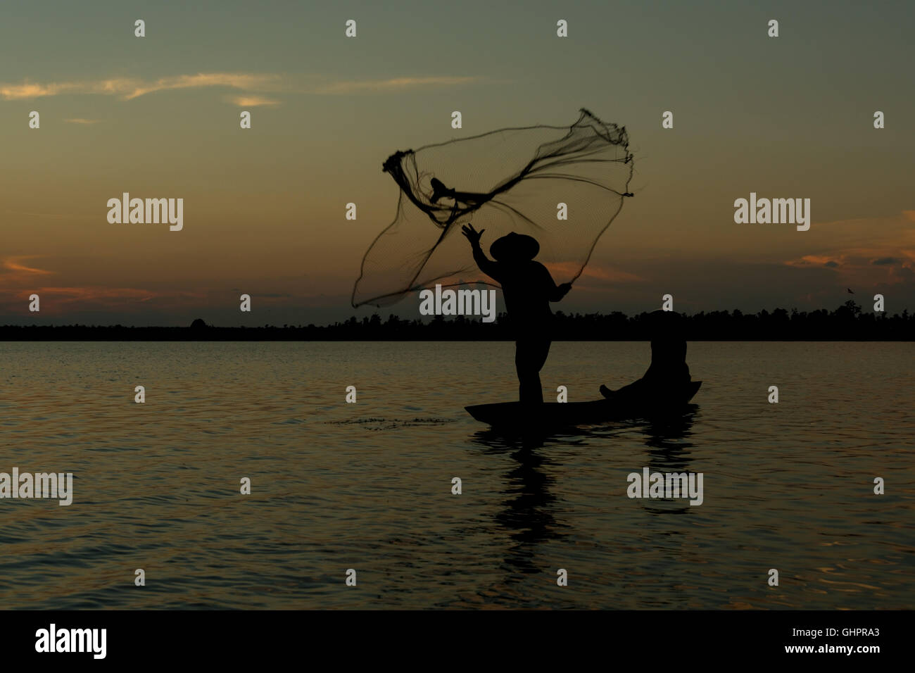Silhouette fisherman on the boat fishing net Stock Photo - Alamy