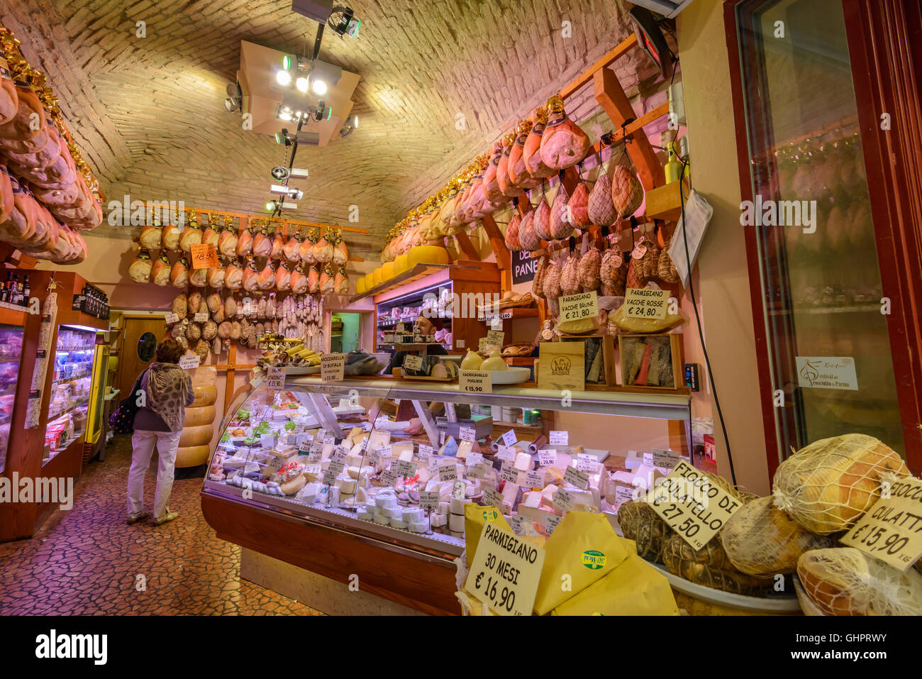 An Italian lady customer is browsing inside of a prosciutto (ham) and cheese shop in Parma, Italy Stock Photo