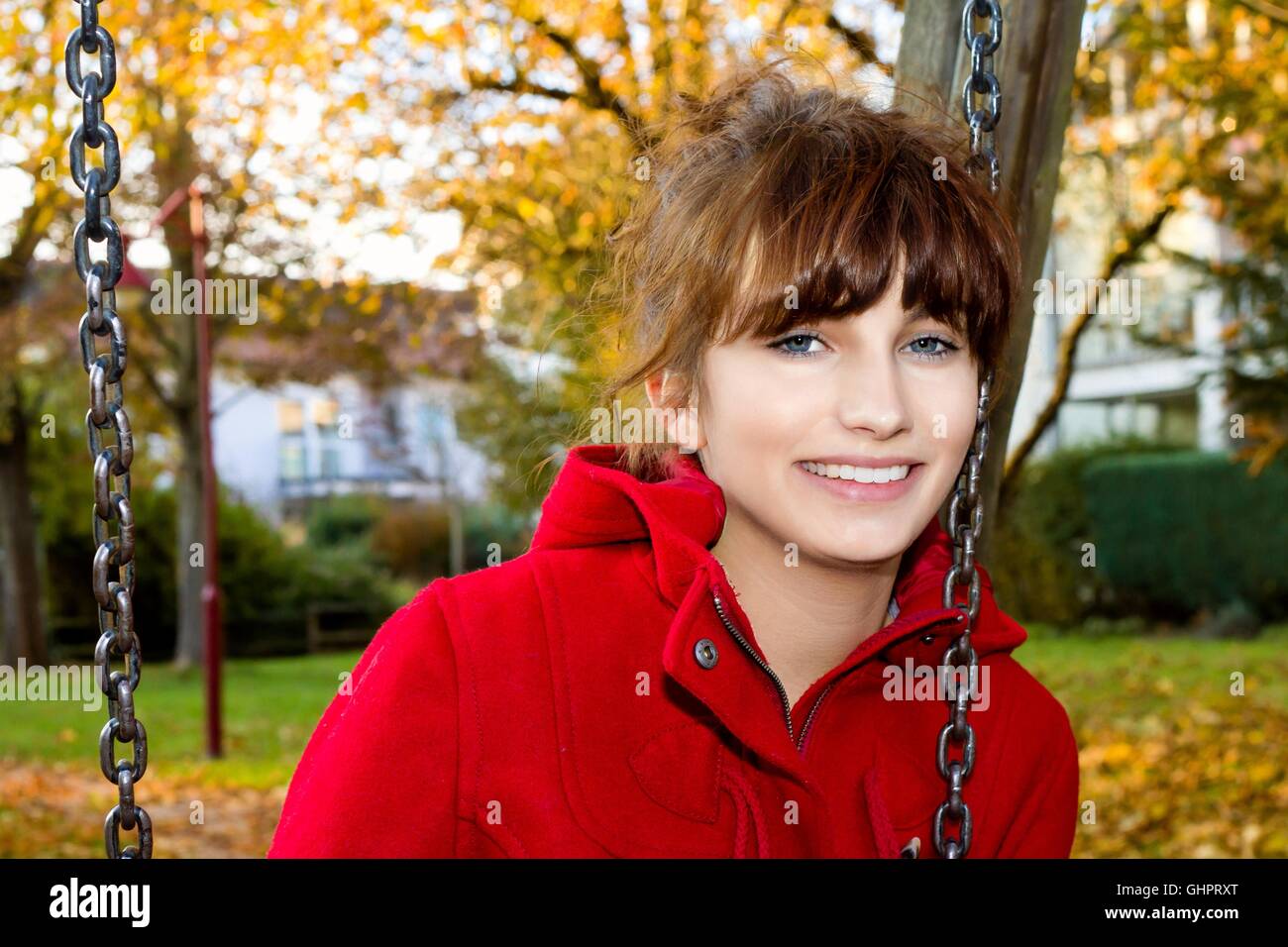 Portrait of a young woman in fall sitting on a swing Stock Photo