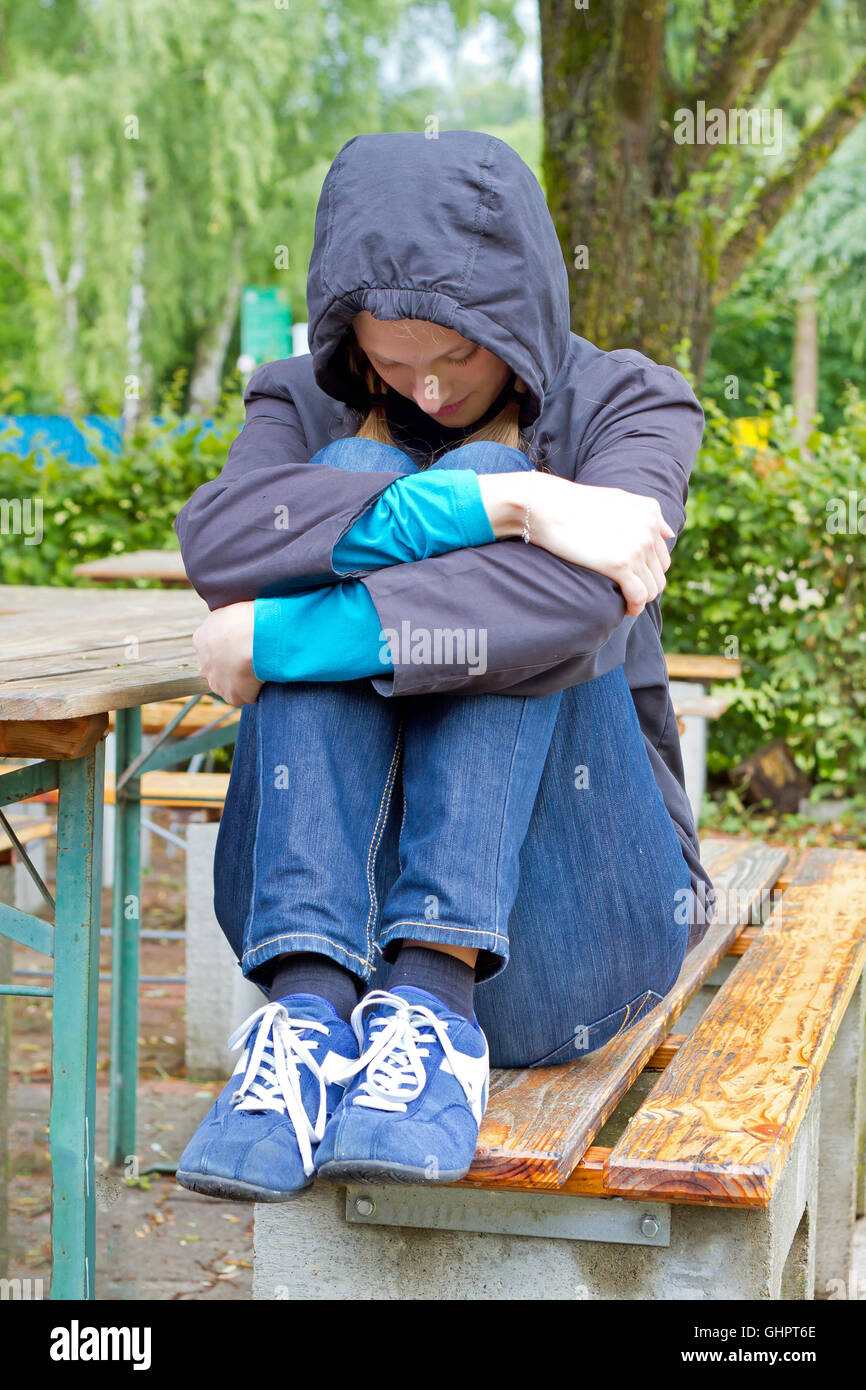 Young sad woman sitting on a lake Stock Photo