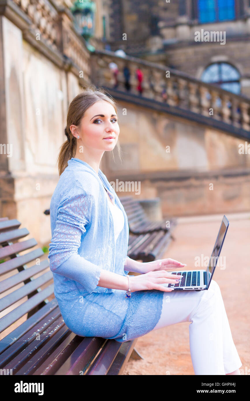 Girl works on laptop sitting on a bench in the park Stock Photo