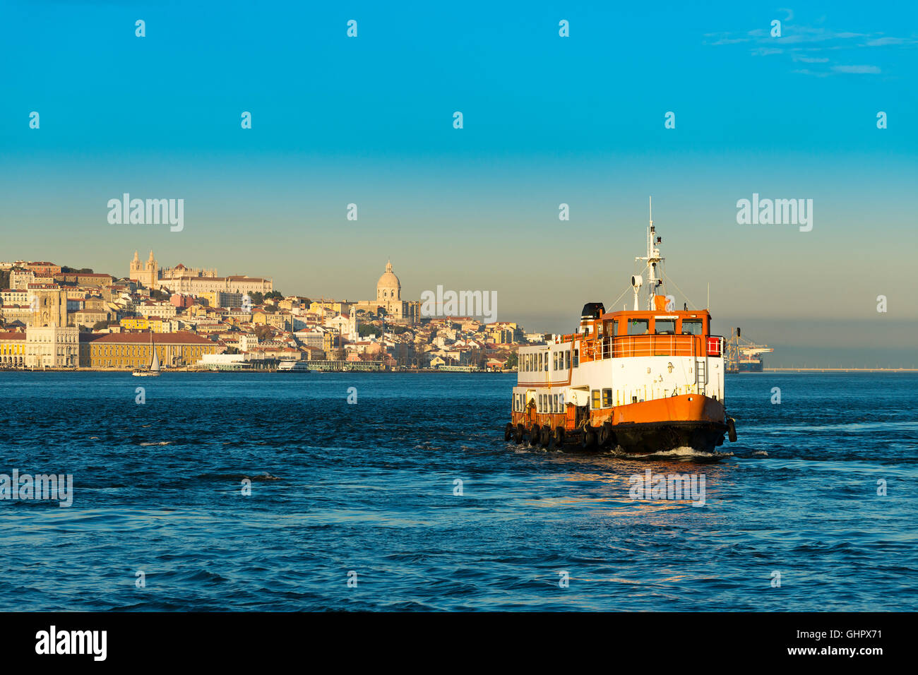 Passenger boat (Cacilheiro) crossing the Tagus River with the Lisbon skyline as background; Concept for travel in Lisbon, Portug Stock Photo