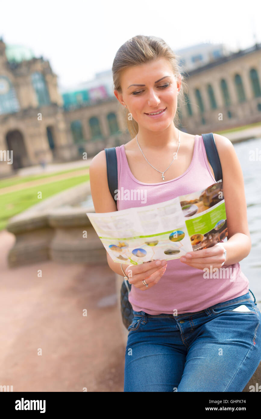 Female tourist reading a travel guide to the Zwinger palace, Dresden, Germany Stock Photo
