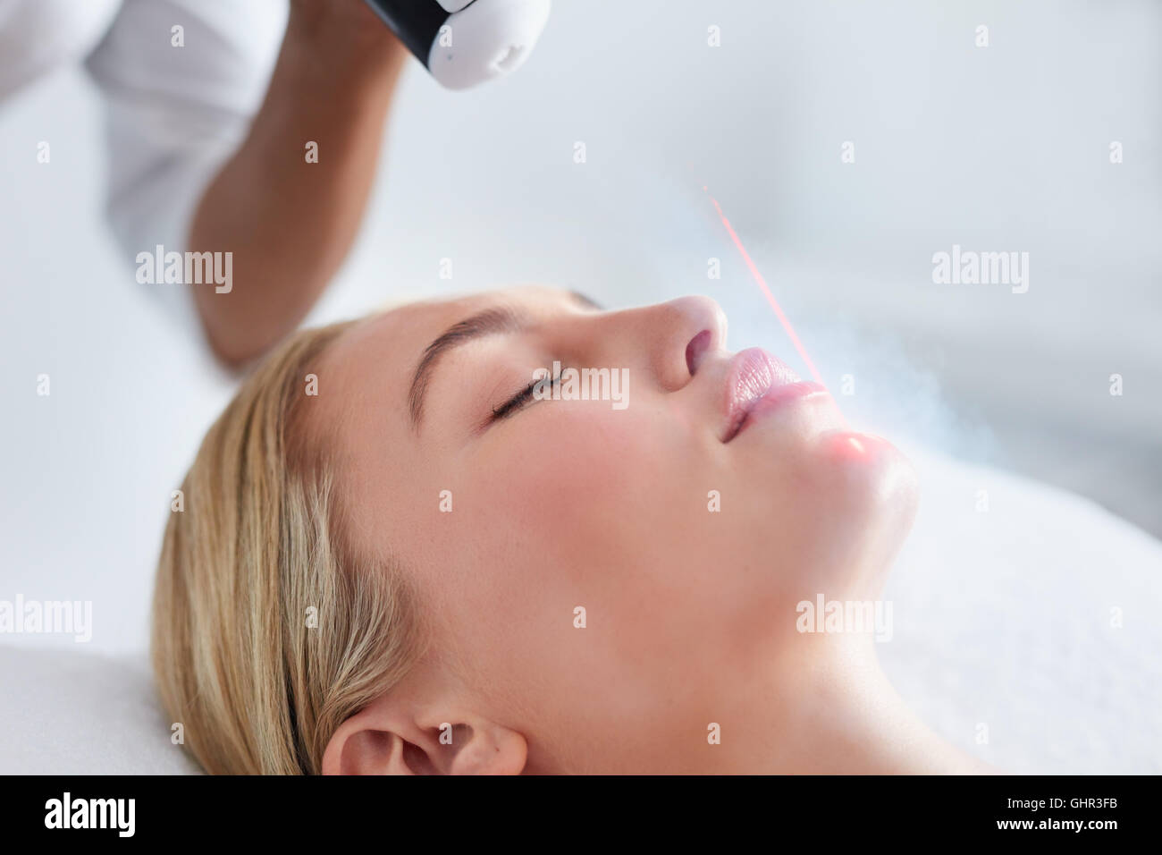 Close up of face of young woman receiving local cryotherapy. Beauty treatment using vaporized nitrogen. Stock Photo