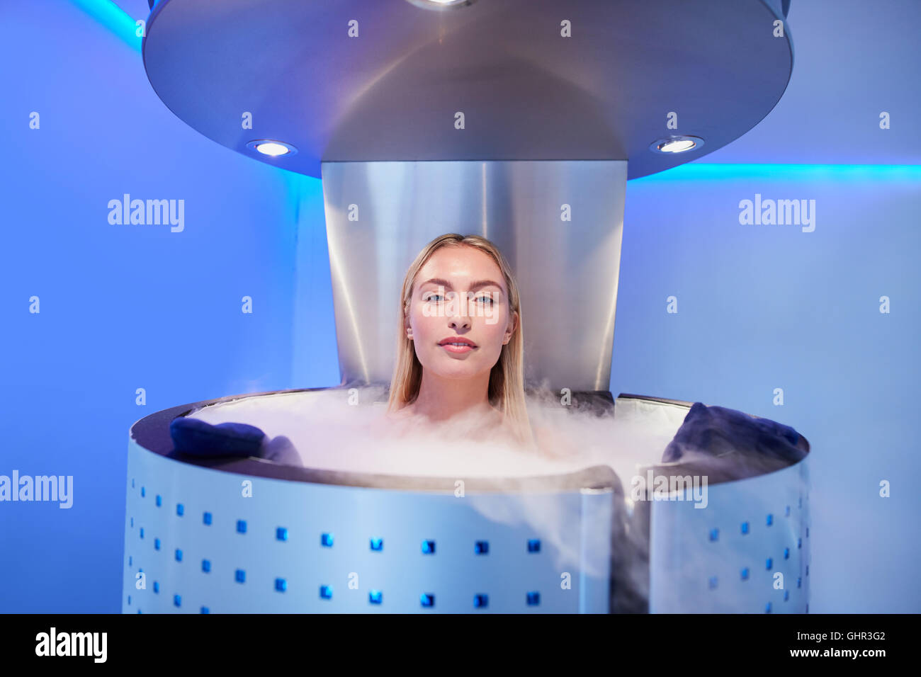 Woman in cryosauna booth for whole body cryotherapy. Caucasian female in freezing chamber with nitrogen vapors. Stock Photo