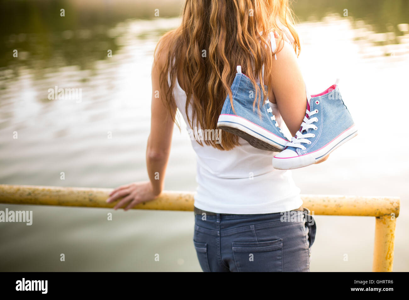 tied pair of jeans sneakers hanging on a finger of a beautiful young woman  over the shoulder Stock Photo - Alamy