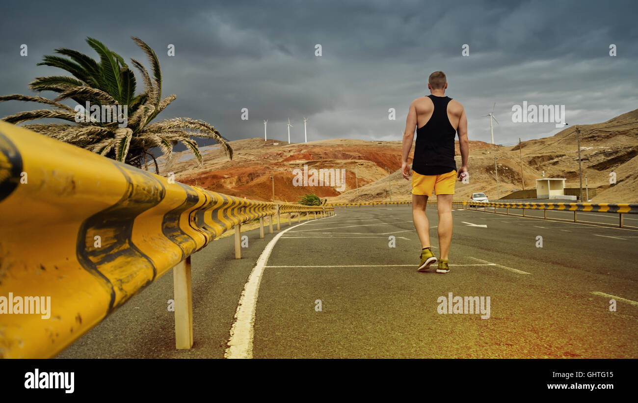 young man as a tourist in a parking lot with guard rails next to a palm tree in Madeira Stock Photo