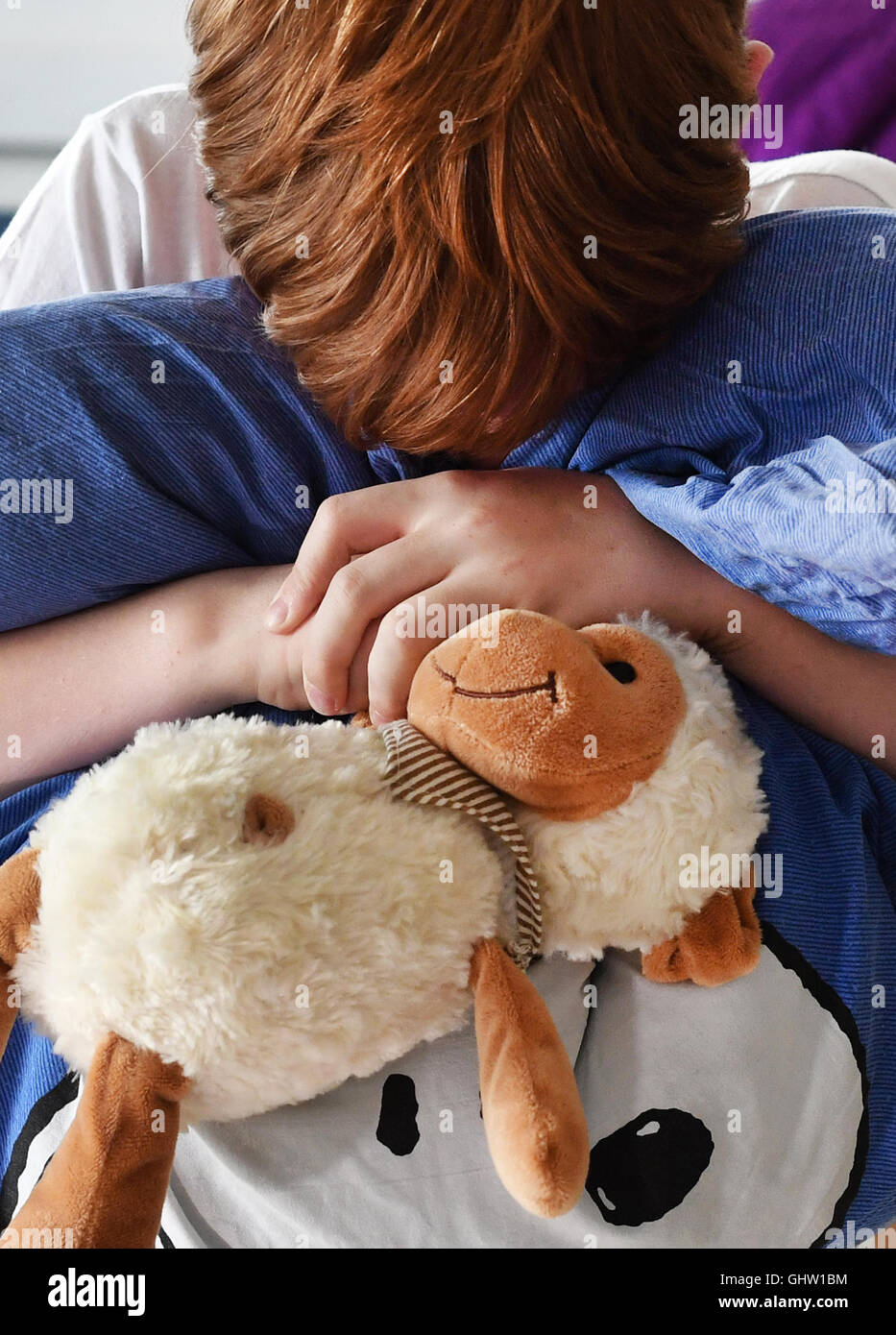 Berlin, Germany. 10th Aug, 2016. ILLUSTRATION - A boy in pyjamas covering his face while holding his plush toy in an apartment in Berlin, Germany, 10 August 2016. PHOTO: JENS KALAENE/dpa/Alamy Live News Stock Photo