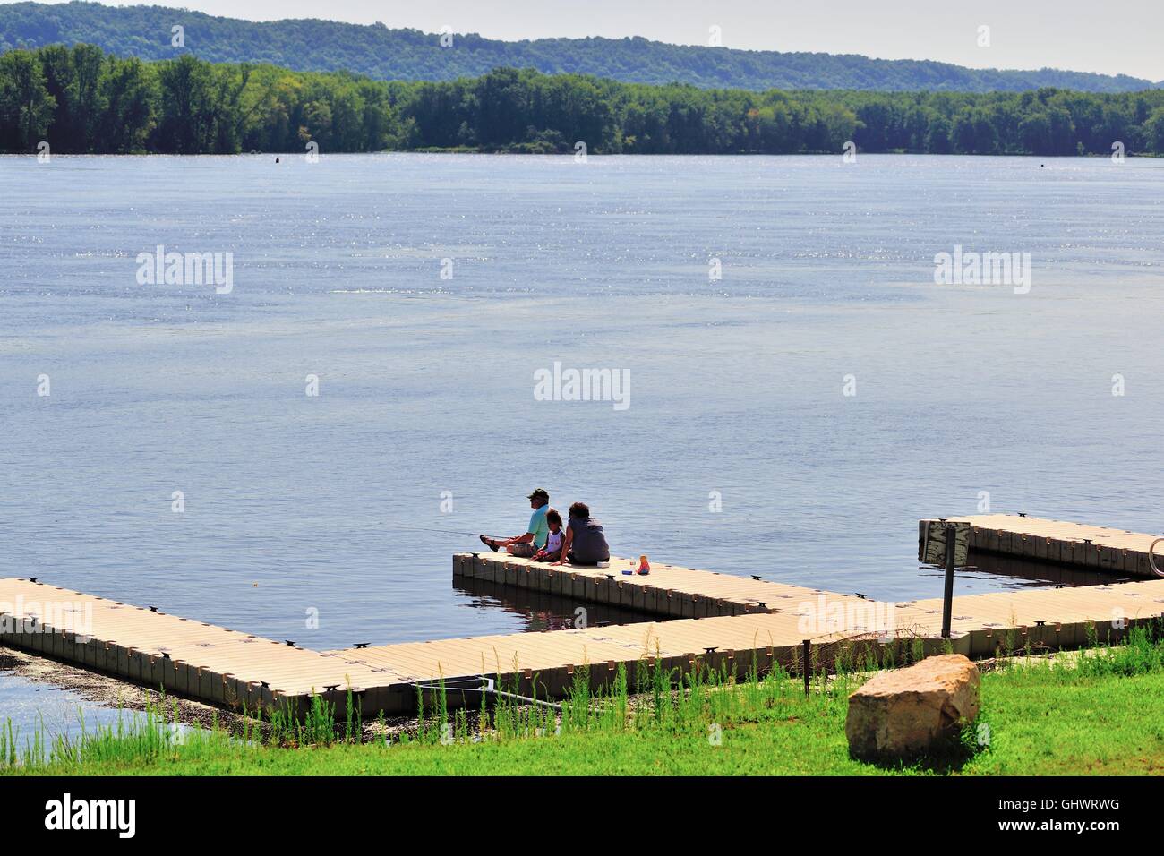 A family fishing the waters of the Mississippi River from a small pier