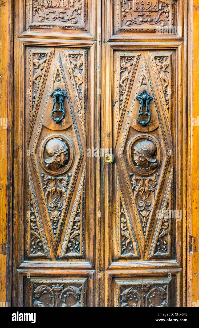 An old Spanish wooden door with the profiles of the heads of Spanish conquistadors in helmets in the Albayzín barrio of Granada. Stock Photo