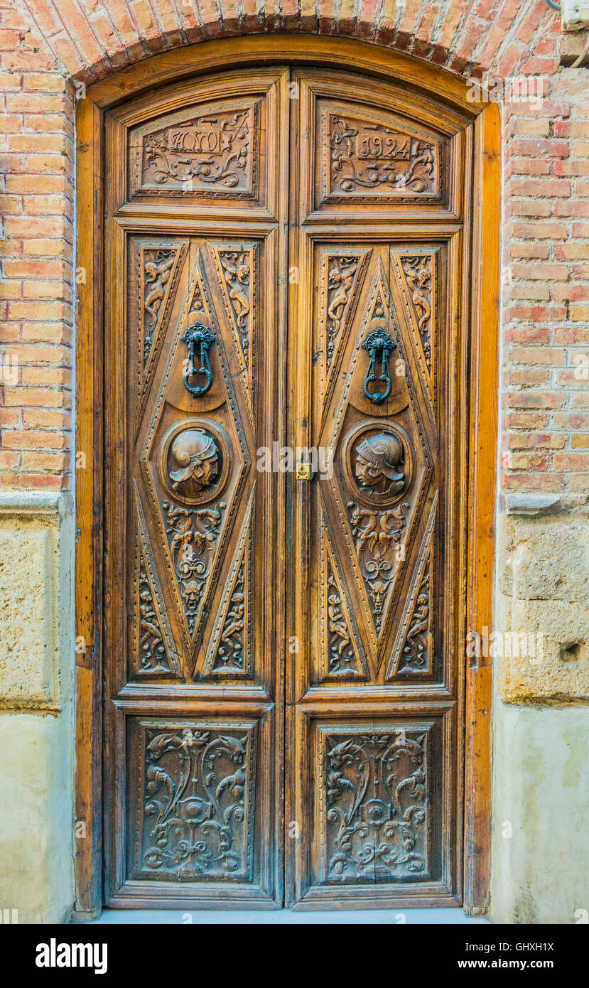 An old Spanish wooden door with the profiles of the heads of Spanish conquistadors in helmets in the Albayzín barrio of Granada. Stock Photo