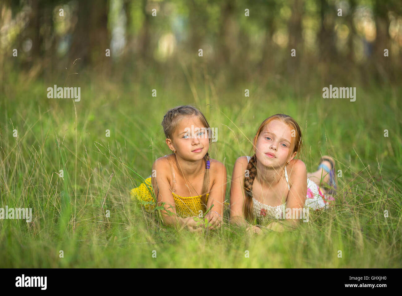 Two little sisters lying in the meadow looking at the camera Stock ...