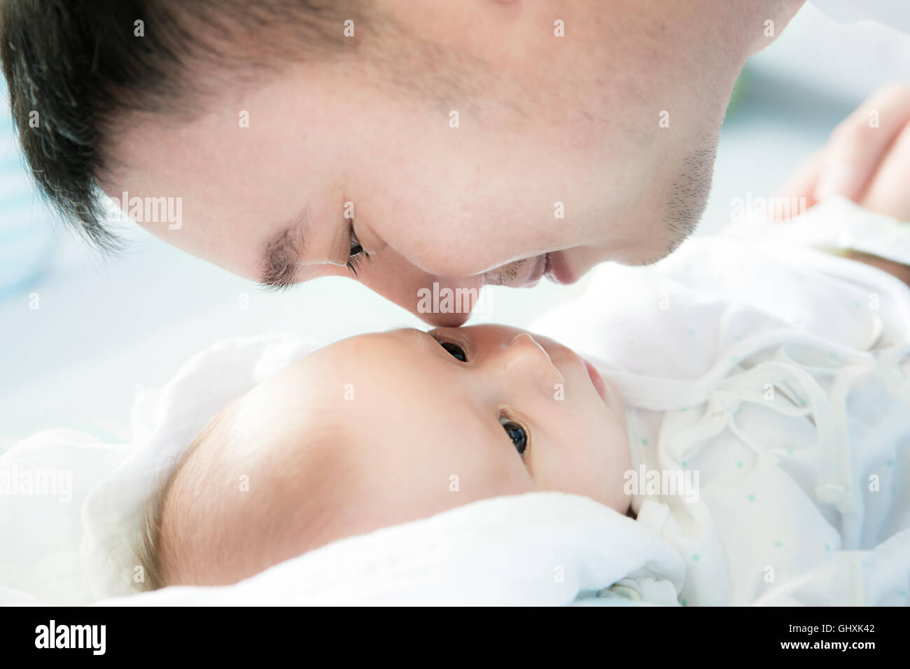 Asian father and infant baby at home lying on the bed together bedtime.Close up at father and infant baby. Stock Photo