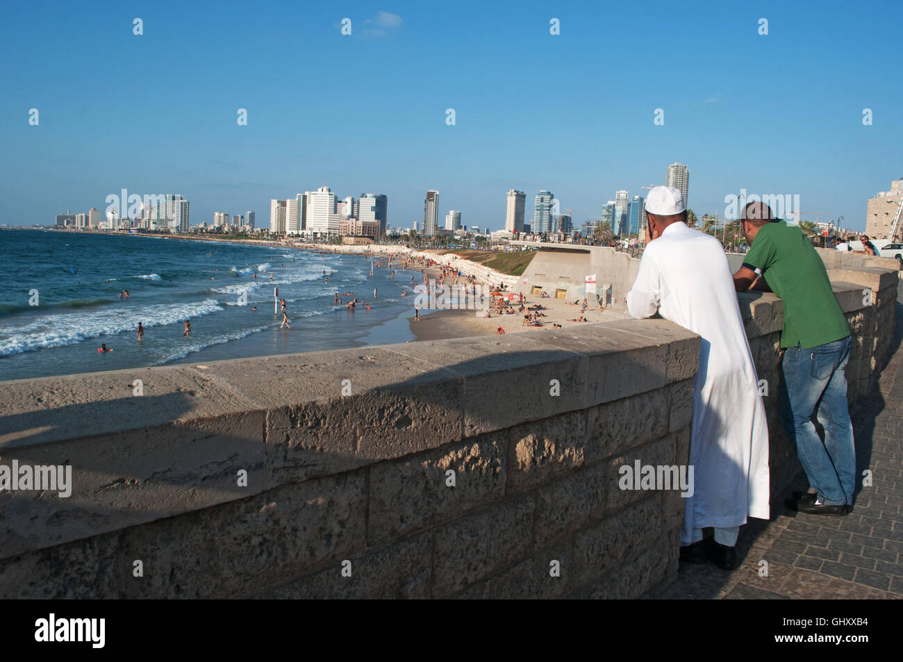 Israel, middle East: muslim men at the promenade of Old Jaffa with view of the Mediterranean Sea and the skyline of Tel Aviv on the background Stock Photo