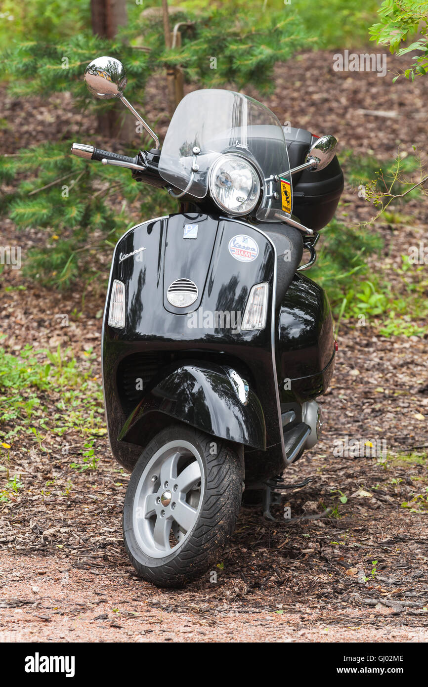 Kotka, Finland - July 16, 2016: Black classical Italian scooter Vespa by Piaggio stands parked in countryside Stock Photo