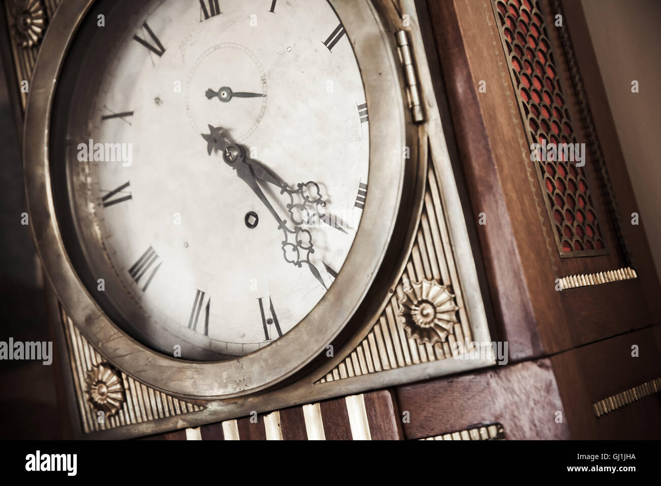 Vintage grandfather clock, decorative wooden body and white dial fragment. Close up photo with warm retro tonal correction photo Stock Photo