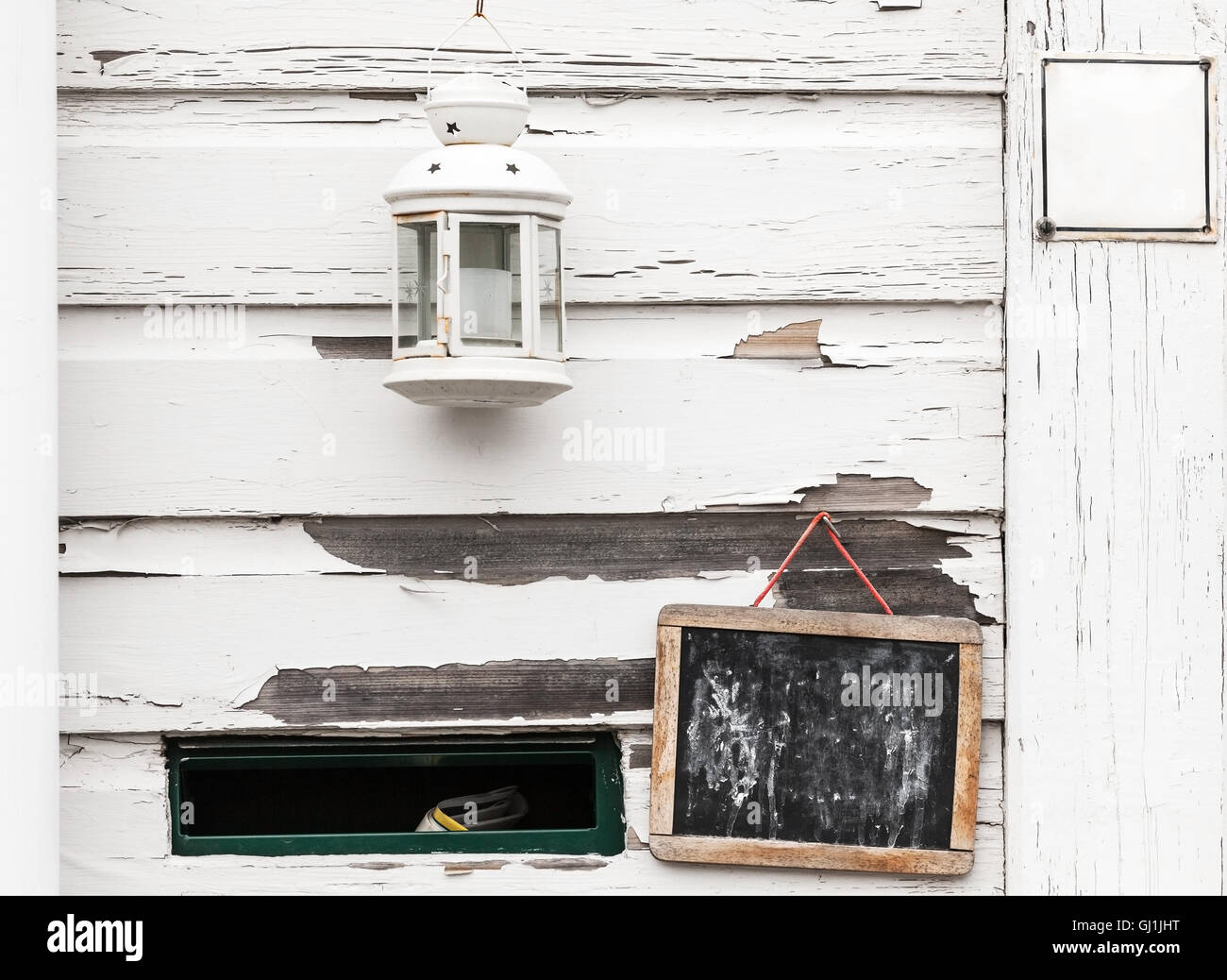 White rural wooden wall with black chalkboard, candle lamp and mailbox hole, background photo texture Stock Photo