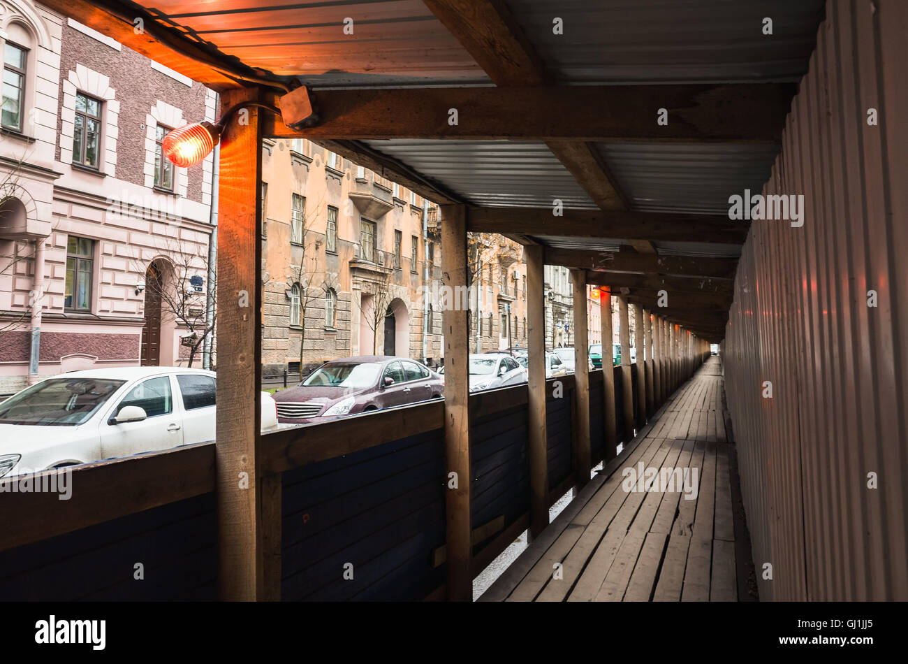 Construction site border with warning red lights, empty wooden protective corridor along the street for pedestrians Stock Photo