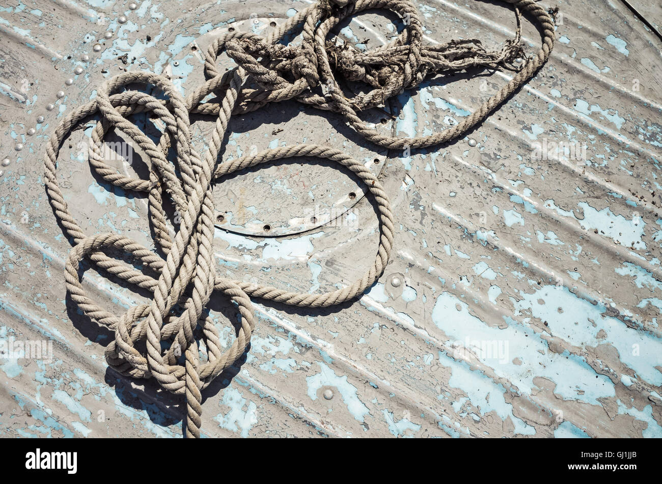 Knotted mooring rope lying on grungy boat deck Stock Photo