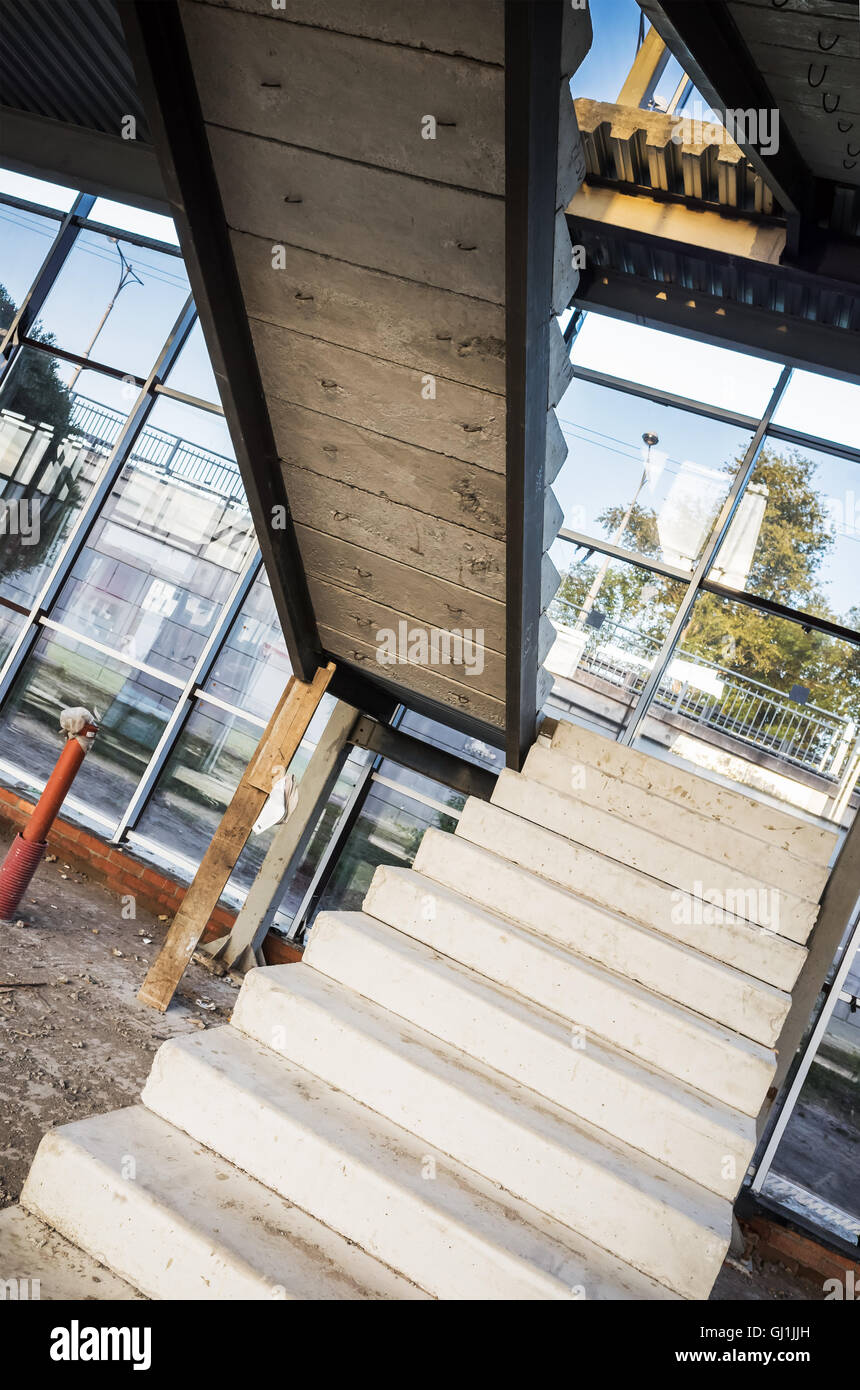 Generic industrial building is under construction. Interior fragment with unfinished concrete stairway, vertical photo with pers Stock Photo