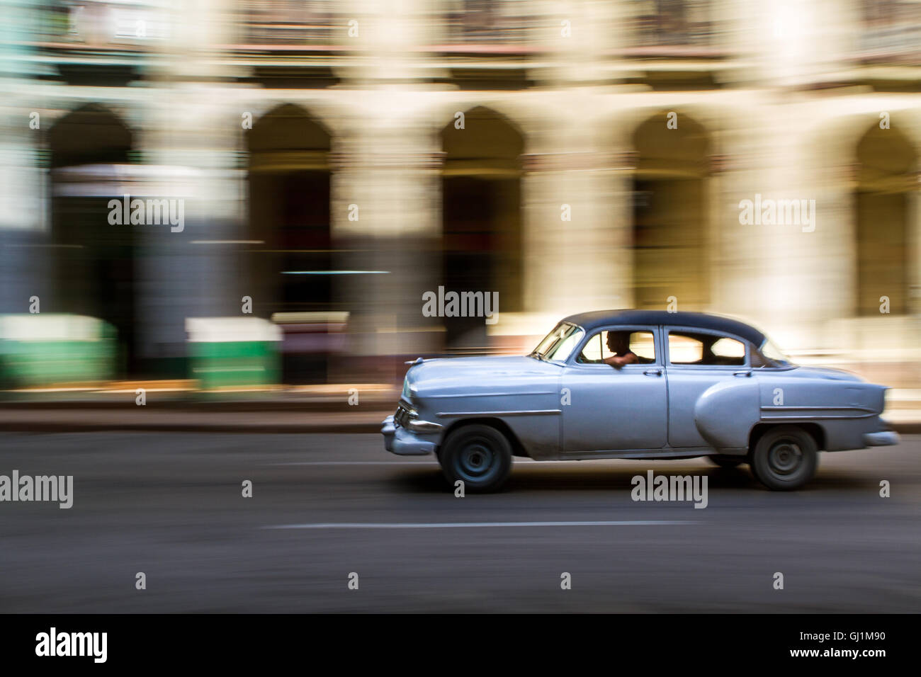Panning shot of classic, grey, vintage American car on sunny day in colonial street, Havana, Cuba, 2013 Stock Photo