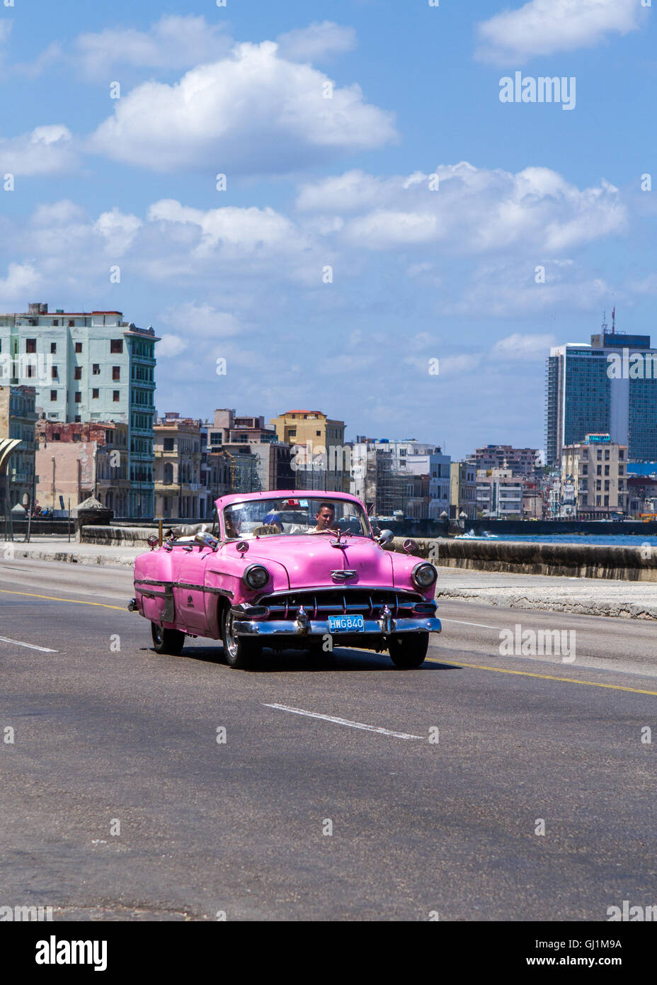 Pink open top vintage car on Malecon by the Caribbean sea, on a sunny day, Havana, Cuba, 2013 Stock Photo