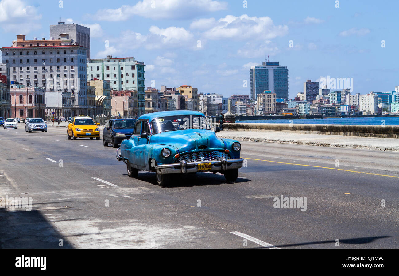 Blue vintage car on Malecon by the Caribbean sea, on a sunny day, Havana, Cuba, 2013 Stock Photo