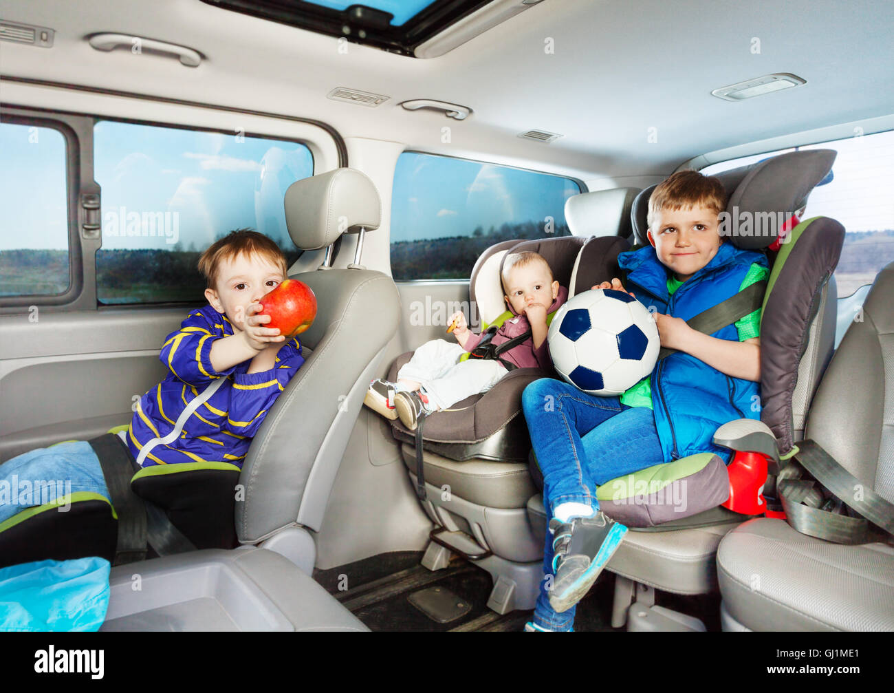 Cute little boys travelling by car in safety seats Stock Photo