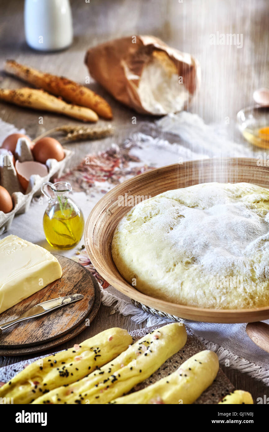 Pouring flour to yeast dough, rustic setting on a wooden table. Stock Photo