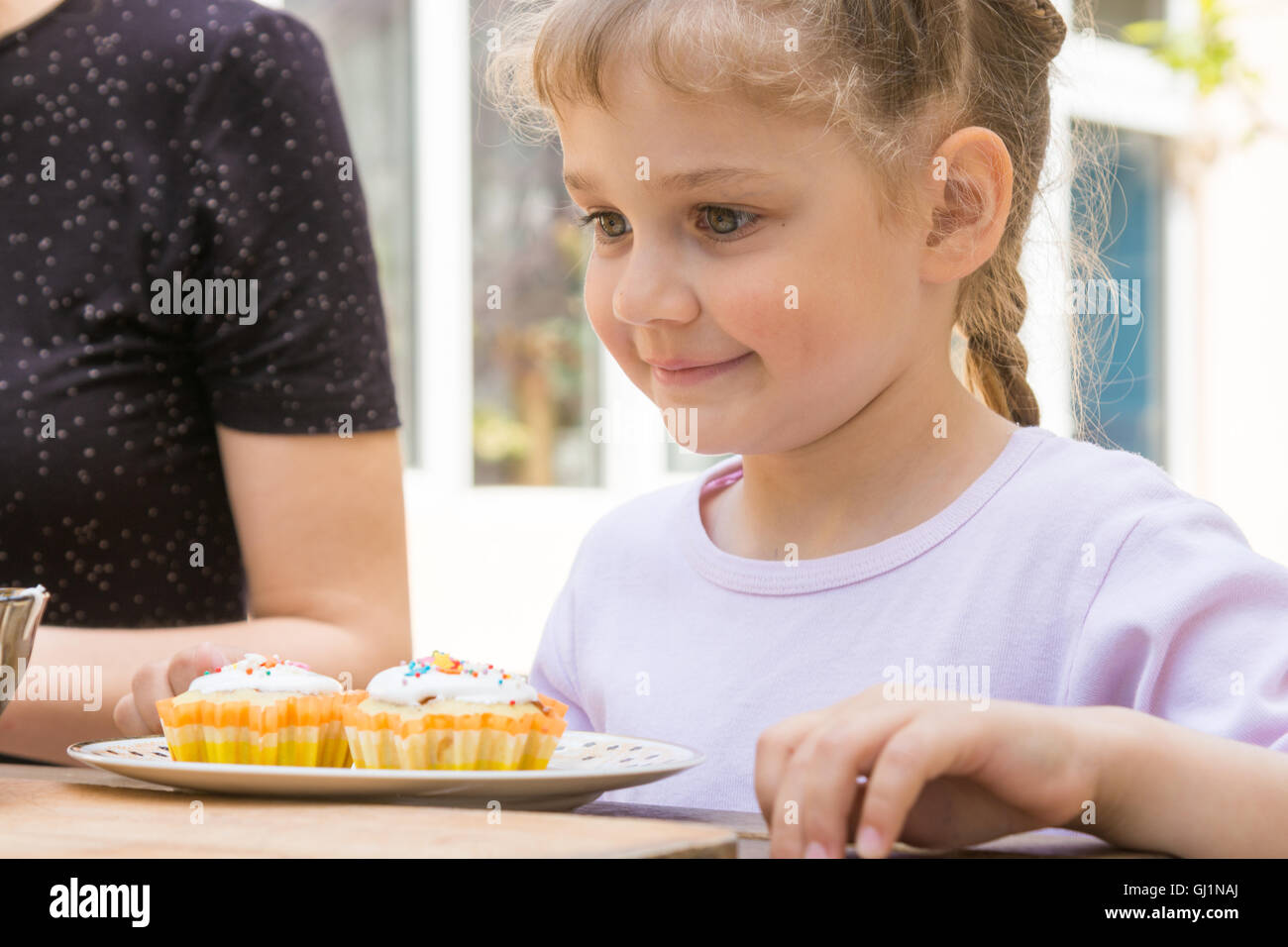 Happy girl is preparing to eat Easter cupcakes Stock Photo