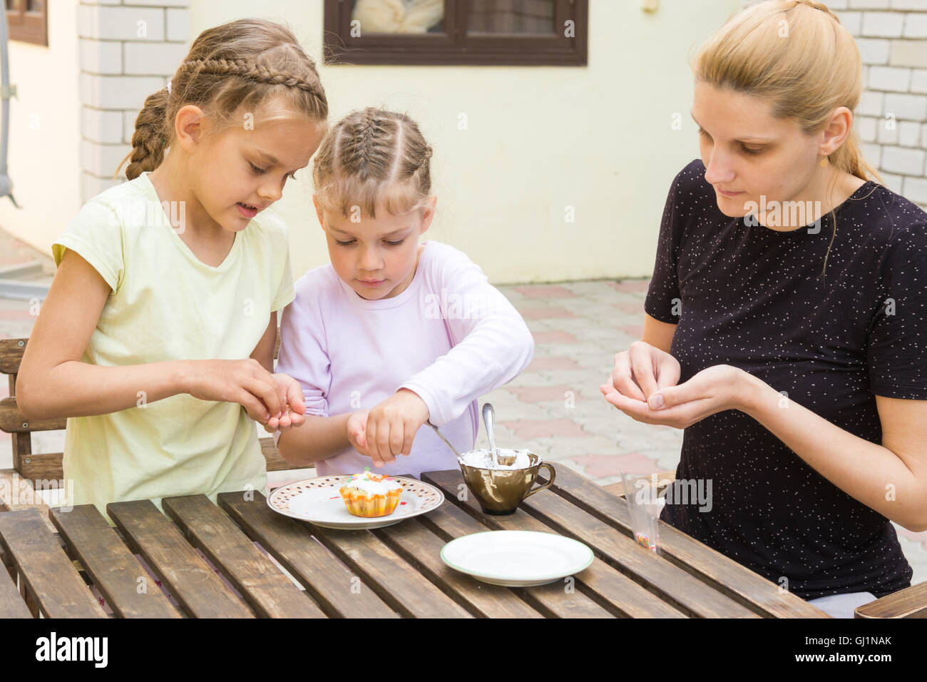 Mother and two daughters are preparing for the holiday Easter cupcakes Stock Photo