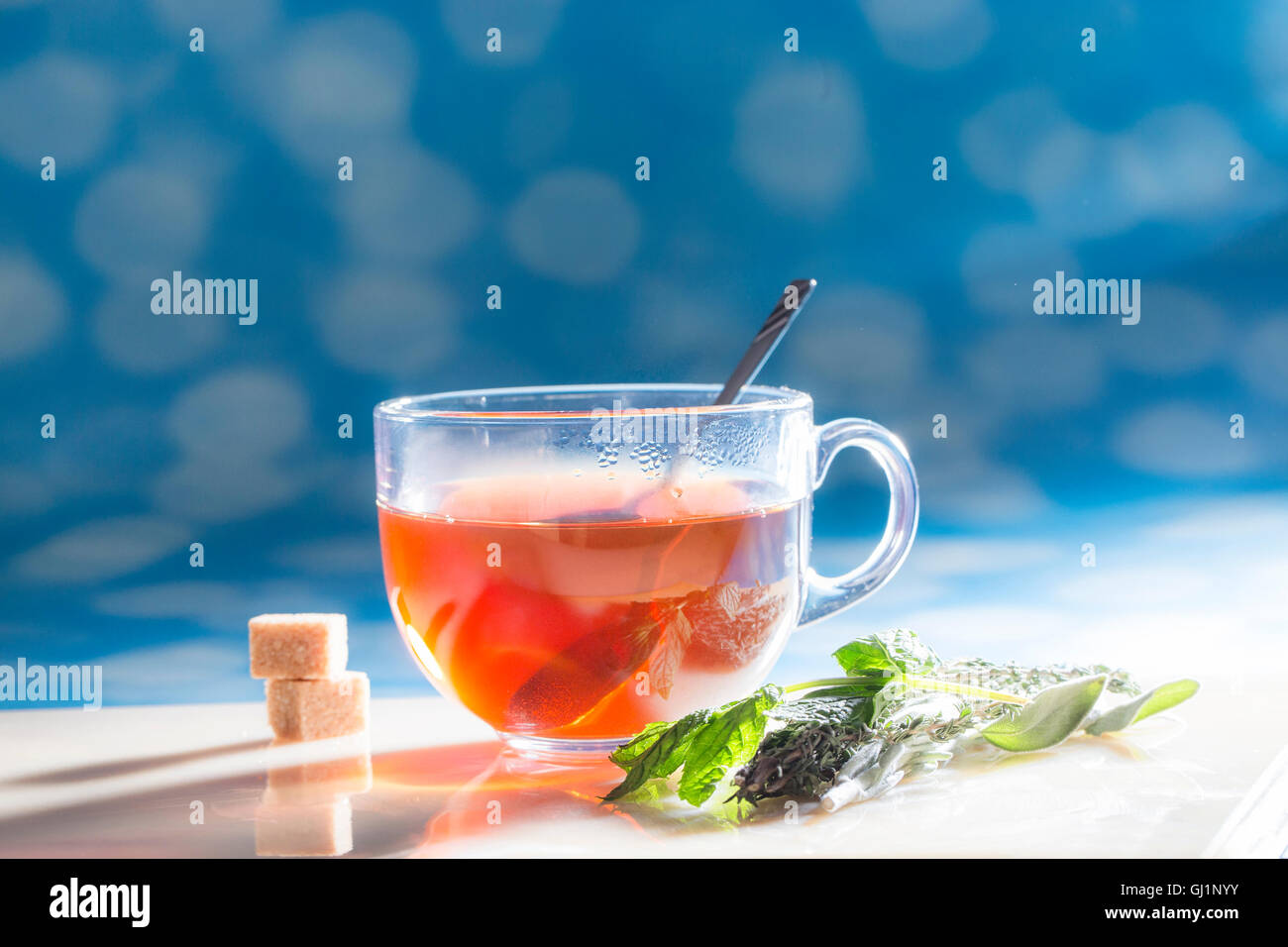 cup of tea with sugar and herbs at sunny day. Stock Photo