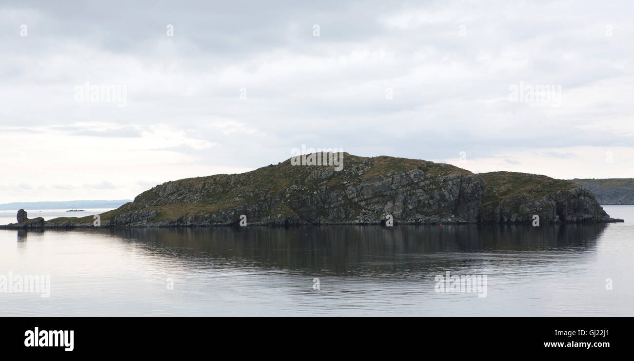 Fergus Island off Bay Roberts in Newfoundland and Labrador, Canada. Heavy, overcast skies hang over the shoreline above Concepti Stock Photo