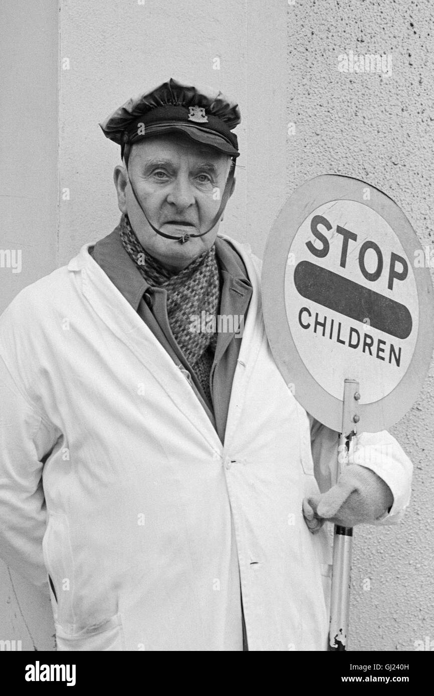 In the UK a school crossing supervisor or school crossing patrol officer is commonly known as a lollipop man or lollipop lady, This photograph is of a lollipop man working in the East end of Glasgow in the early seventies Stock Photo