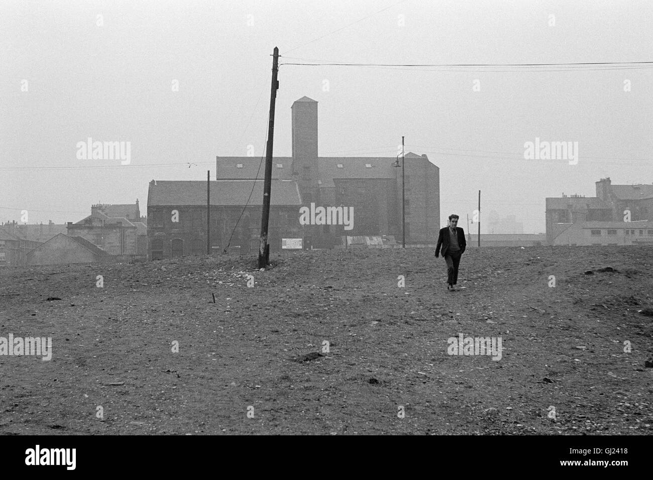 Man walking across waste ground, East End Glasgow 1971 approx Stock Photo
