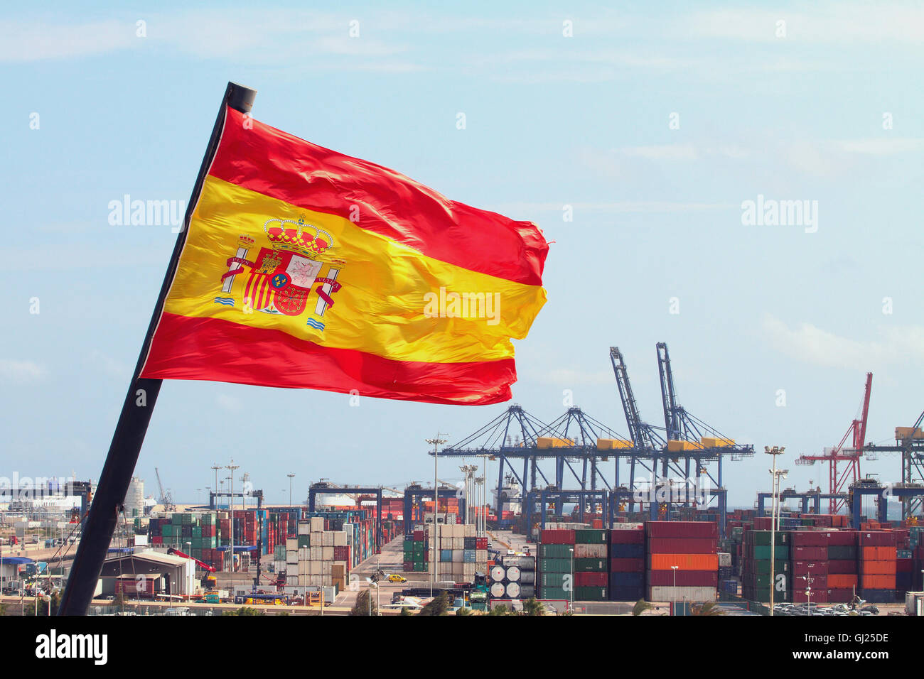 Fluttering flag of Kingdom of Spain and cargo port, Valencia Stock Photo