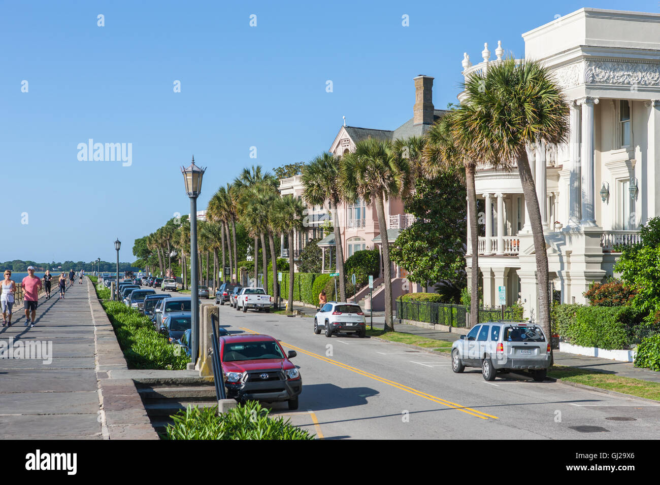 People walk and jog across from historic antebellum mansions on Battery Row, in Charleston, South Carolina. Stock Photo