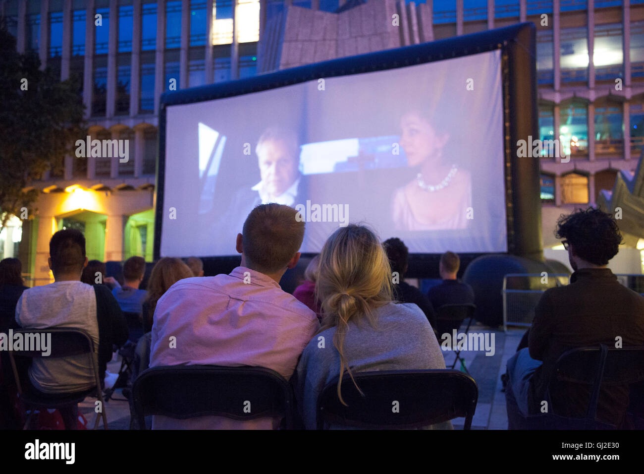 Couple watching a film at an outdoor pop-up cinema (in Guildhall Yard, London, UK) Stock Photo