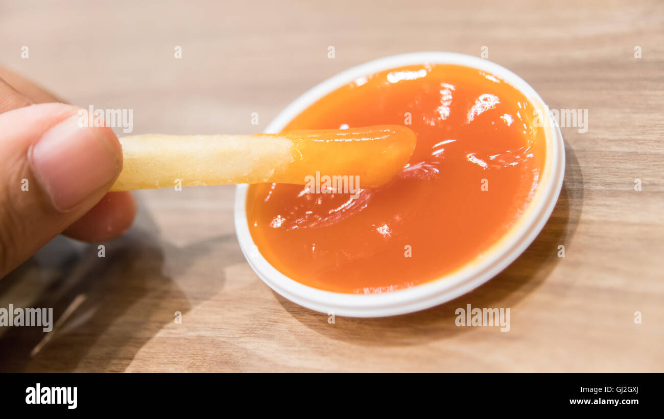 Woman hand being dipped in ketchup Stock Photo Alamy