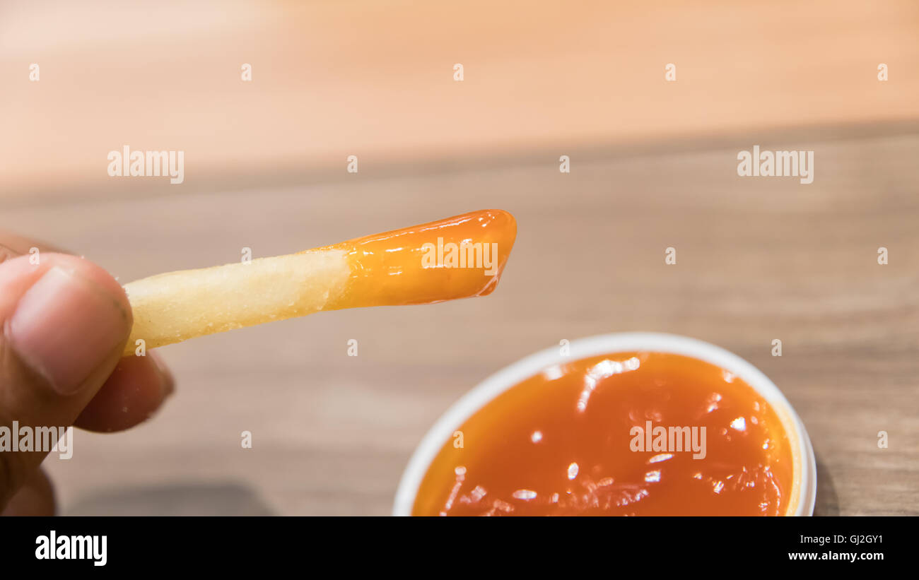 Woman hand being dipped in ketchup Stock Photo Alamy