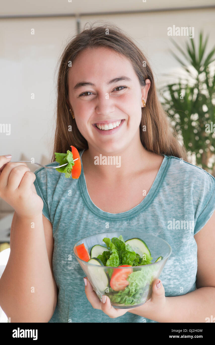 Teenage girl holding bowl of salad looking at camera smiling Stock Photo