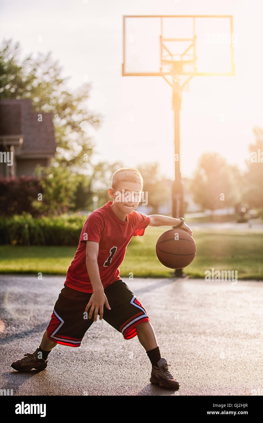 Portrait of young boy dribbling with basketball Stock Photo