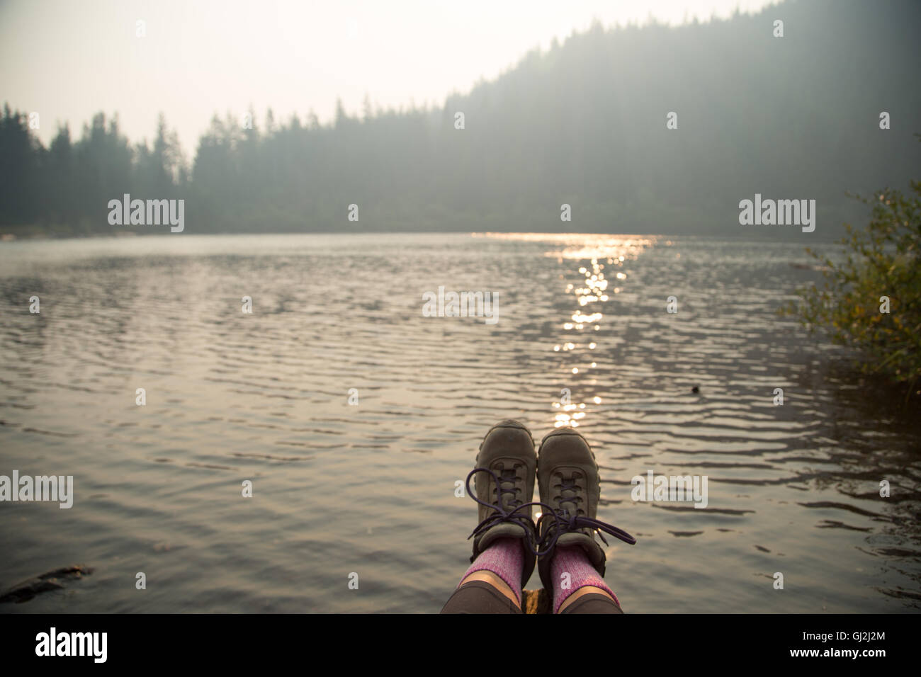 Female feet wearing hiking boots over lake, Mount Hood National Forest, Oregon, USA Stock Photo