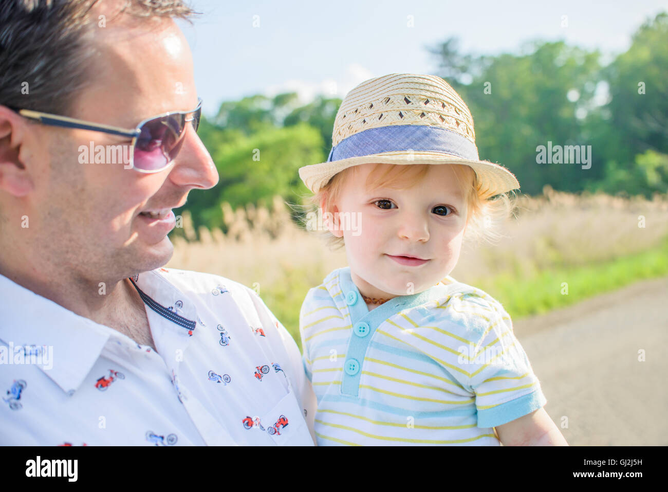 Father holding baby boy wearing straw hat Stock Photo