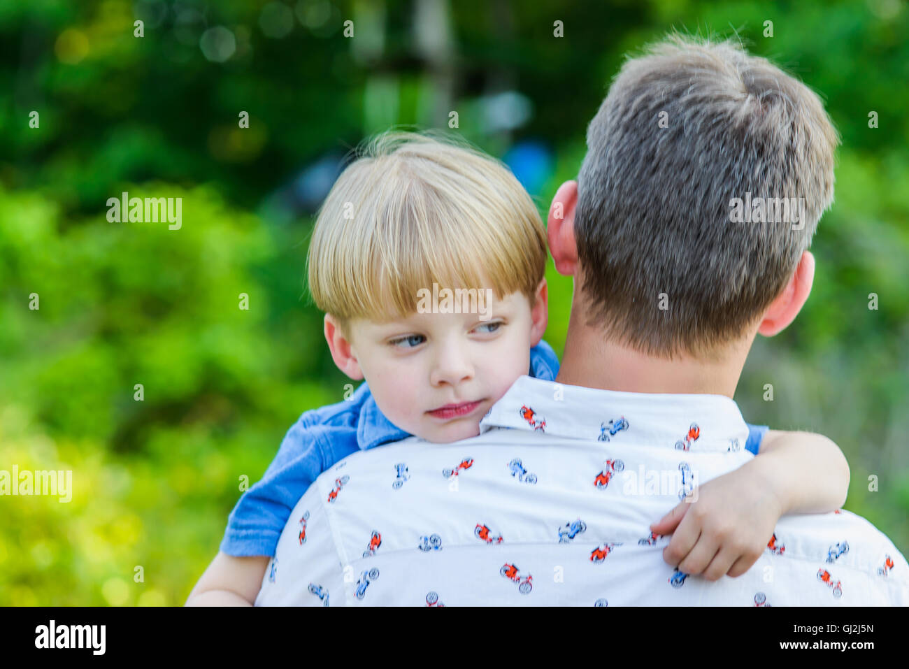 Boy looking away over fathers shoulders Stock Photo