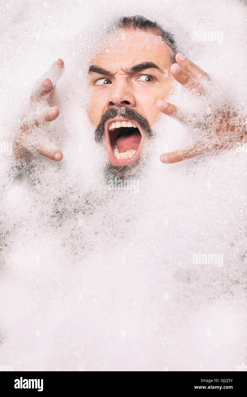 Man with moustache covered in bubbles pulling face Stock Photo